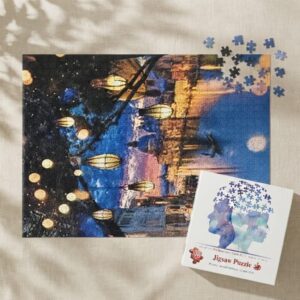 Нареден пъзел 1000 части „Вечерни фенери“ с кей и хартиени фенери над водата, до кутията на светъл лен